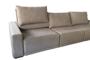 A imagem mostra um espaço com fundo totalmente branco. No centro da imagem encontra-se uma parte do sofá soft na cor marrom.